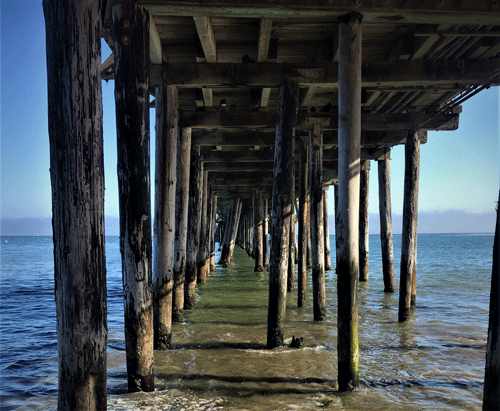 view from standing on beach under docks looking out at ocean along california's pacific coast