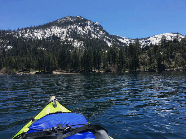 kayak and life jacket in foreground, fallen leaf lake and tahoe mountain backdrop in middle, blue sky in background