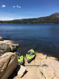 two bright green kayaks at edge of silver lake california on rocky shoreline