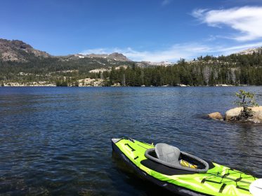 bright green kayak on dark blue water of silver lake near kirkwood calfironia with mountains in background