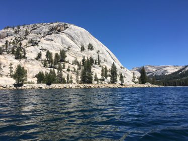 dark blue water of tenaya lake with yosemite's granite dome behind it, photo taken from kayak