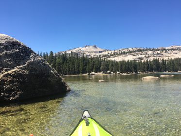 kayak in yosemite's tenaya lake with granite peaks and domes above it