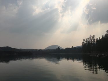 view of cindor cone volcano rising above butte lake, photo taken from kayak on a smokey summer day