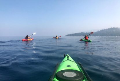 four kayaks crossing smooth water of lake tahoe