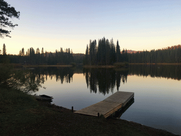 simple wooden dock reaching out onto surface of serene lake at sunset