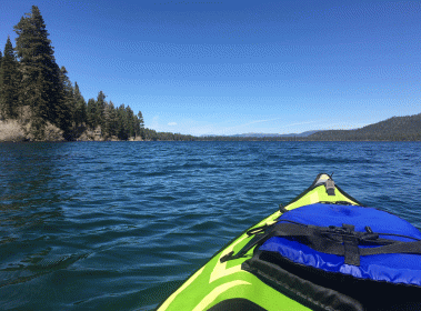 bright green kayak with blue lifejacket in fallen leaf lake with smallpiece of land on top right corner of photo