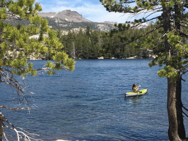 green kayak in silver lake near lake tahoe california. background is pine trees, granite mountaintops. lake is a deep blue shade.