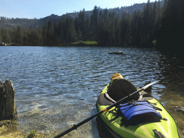 kayaking gold lake in northern california, picture of green kayak near shore with view in background of clear lake and dark green pine trees